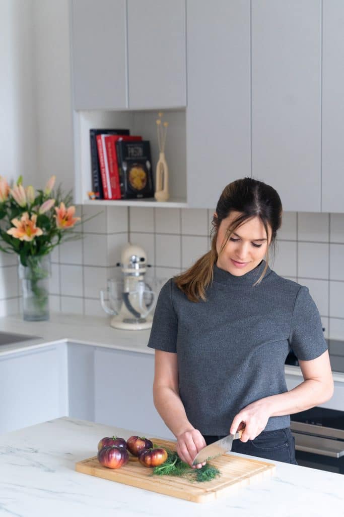 Frontalansicht einer Bloggerin, das in einer Küche Tomaten schneidet