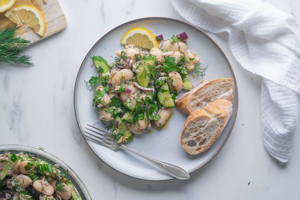 Blick von oben auf einen Teller weißer Bohnen-Salat mit Thunfisch auf weißem Hintergrund