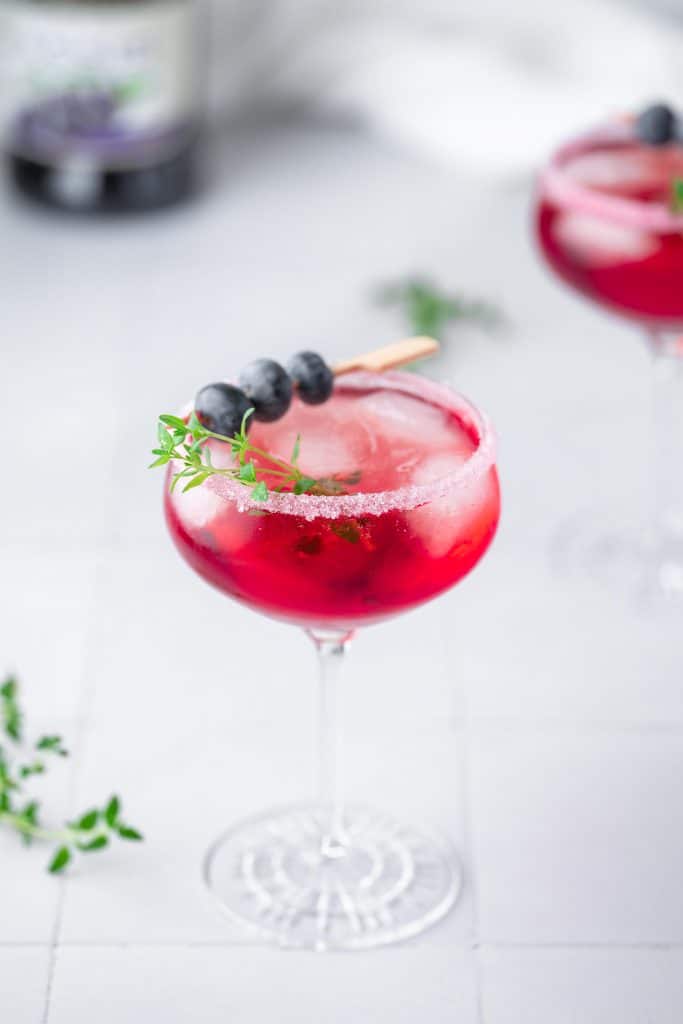 Zoom on Crème de Cassis Cocktail decorated with thyme and blueberries