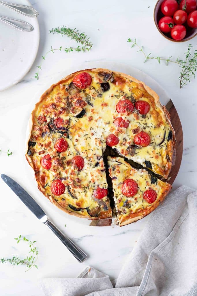 Vegetable and feta quiche seen from above with a cut piece