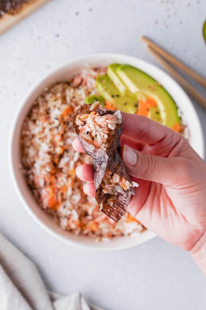 Zoom auf eine Hand, die das berühmte TikTok-Reisrezept mit Lachs isst