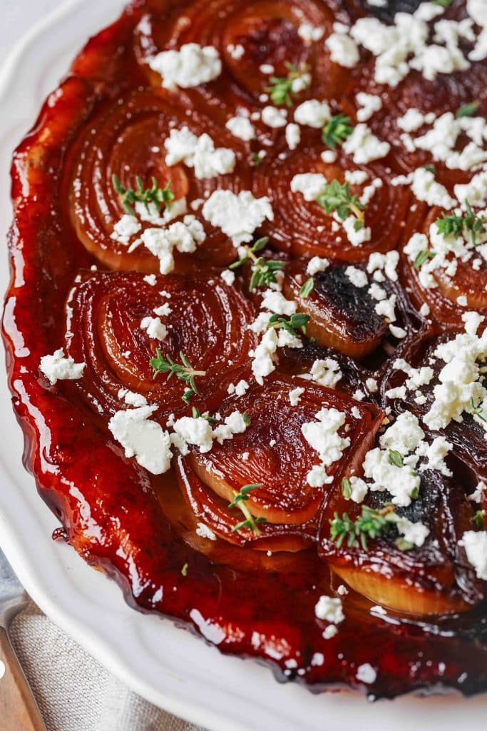 Zoom on a caramelized onion Tarte Tatin with crumbled fresh goat cheese and thyme