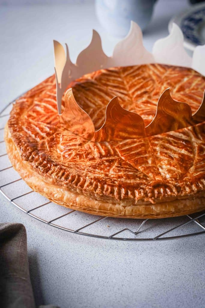 A view of a French Galette des Rois from the top with a paper crown on it