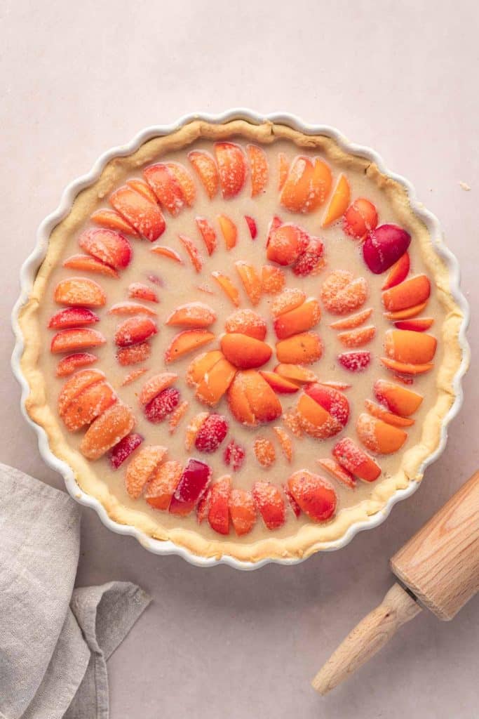 Une tarte à l'abricot et à la crème d'amande dans un moule à tarte avant la cuisson.