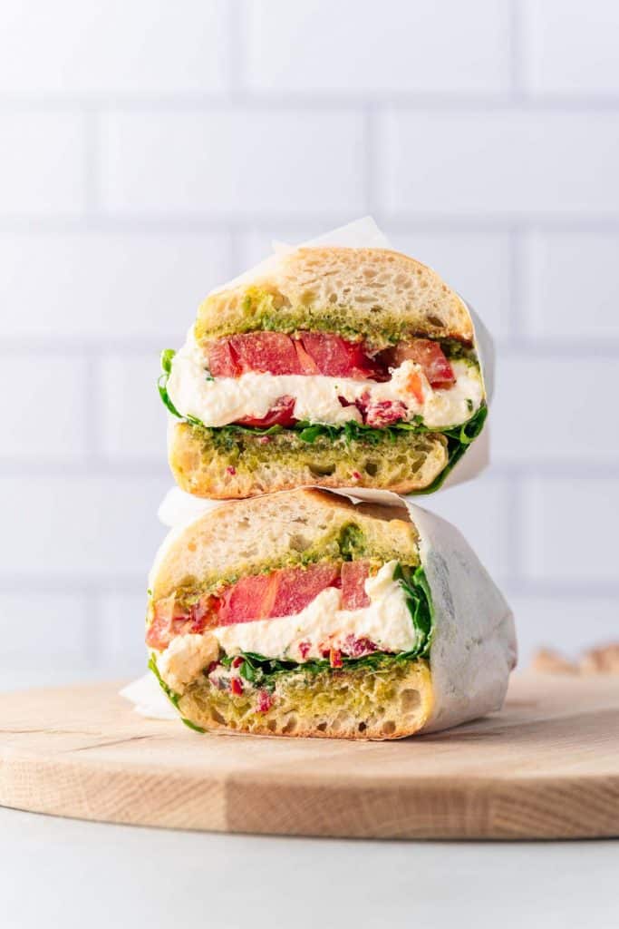 Sandwich à la burrata et à la tomate au pesto coupé en deux 