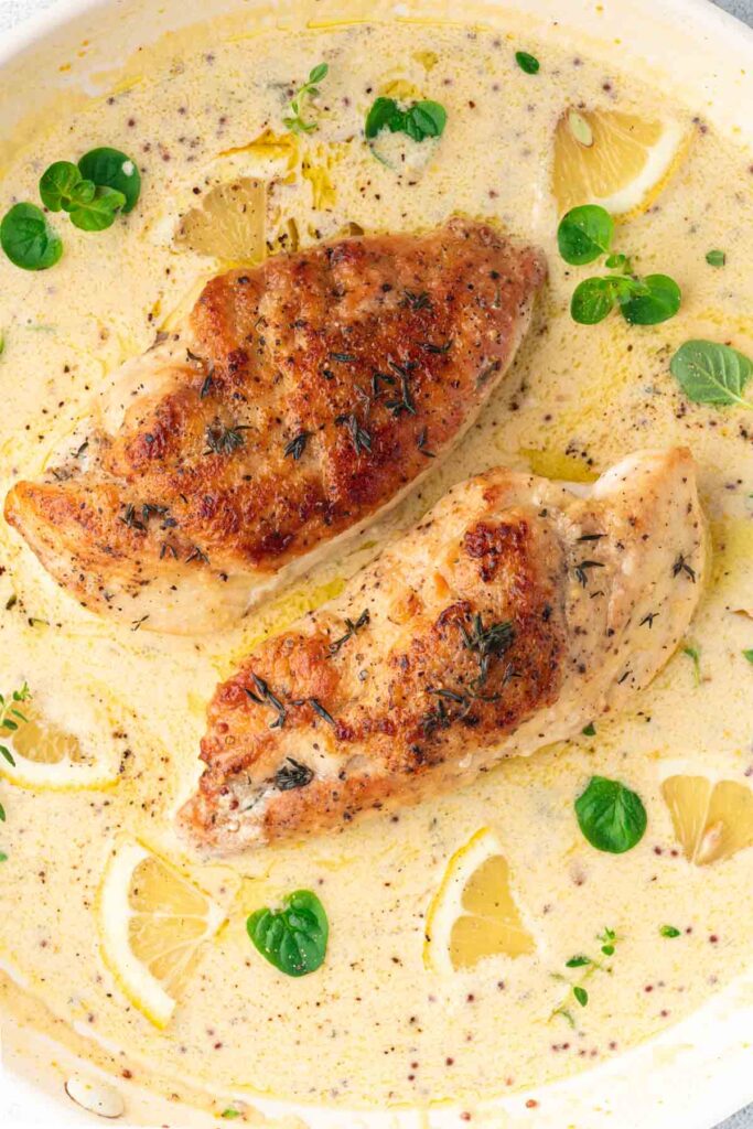 Two creamy Dijon mustard Chicken breasts (poulet à la moutarde) in a skillet