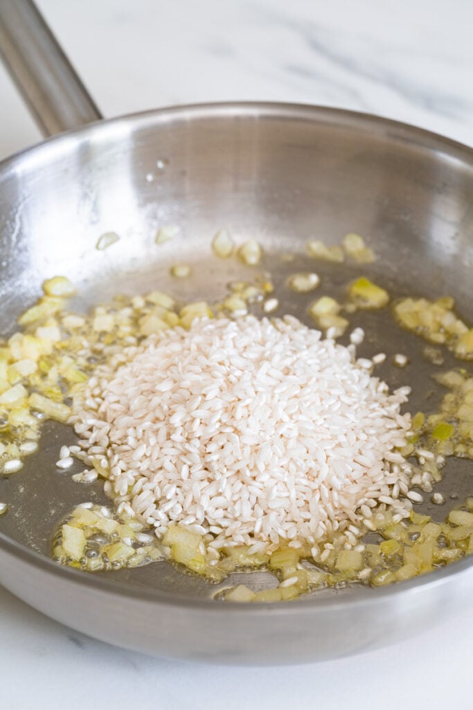 Zwiebeln, die mit Reis in einer Pfanne angebraten werden 