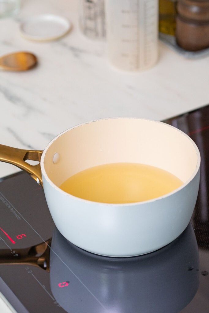 A sky-blue saucepan containing a brine solution for making mustard seed pickles.