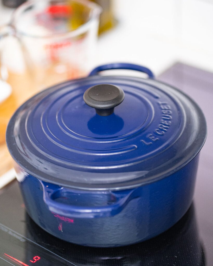 A blue cast-iron pot with a lid on a stove.