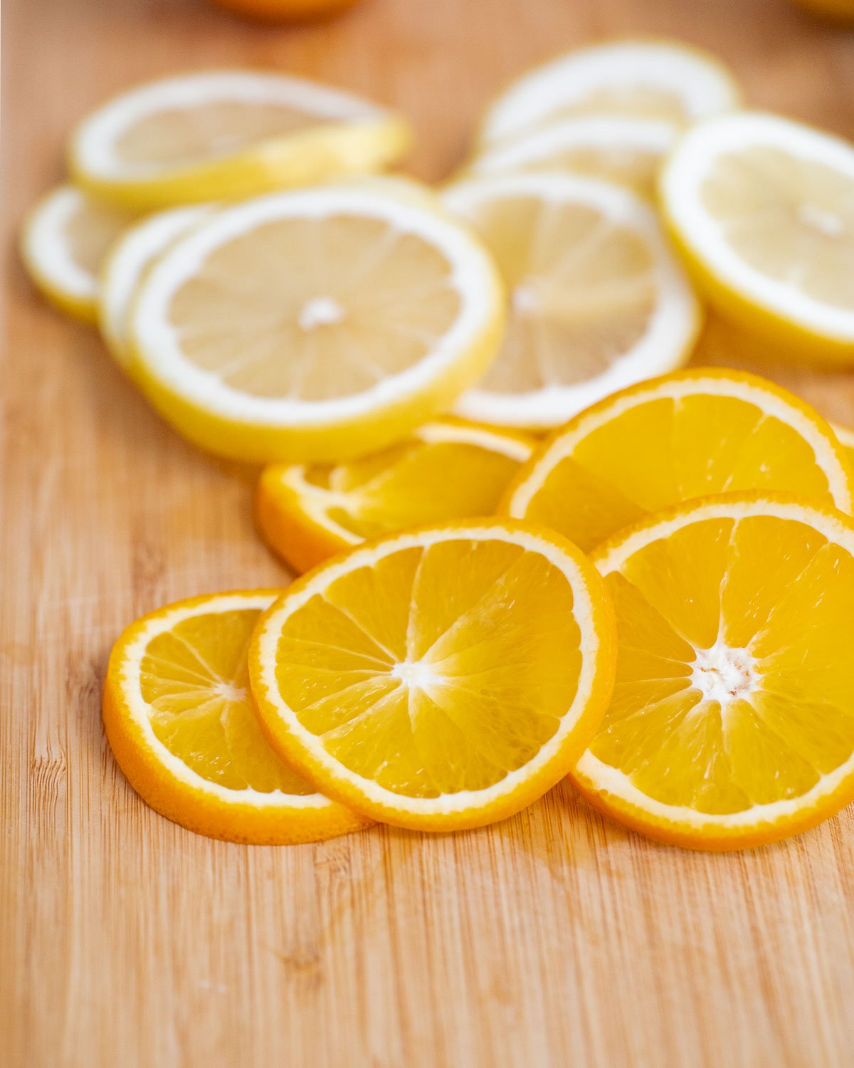 Lemon and orange slices on a wooden cutting board.