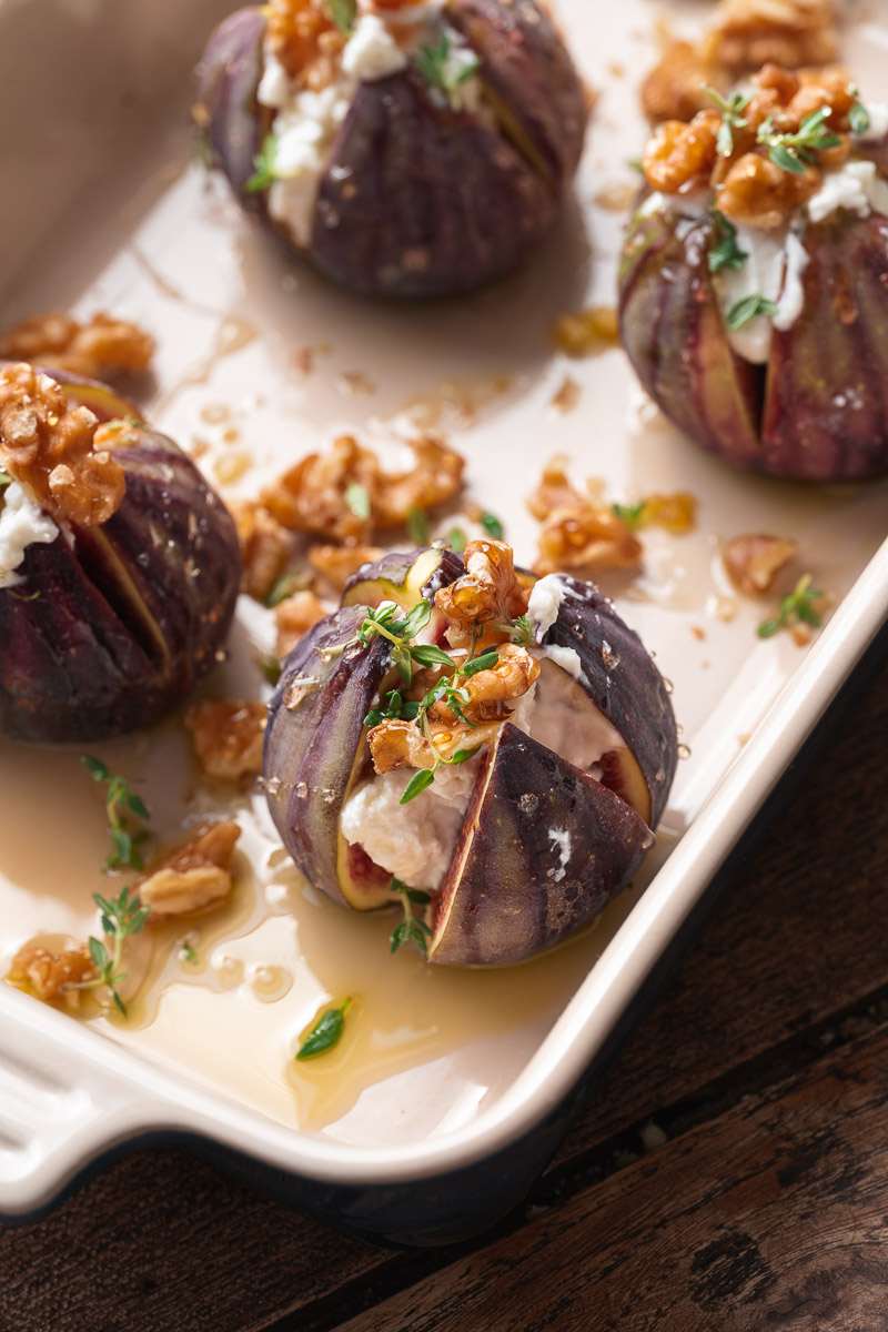 Figs cut in half, stuffed with cheese, garnished with walnuts and fresh herbs, arranged in a baking dish, and drizzled with a little honey.
